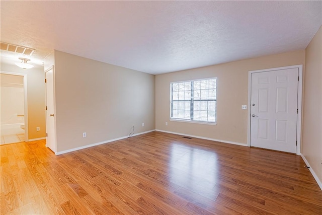 empty room featuring a textured ceiling and light hardwood / wood-style floors