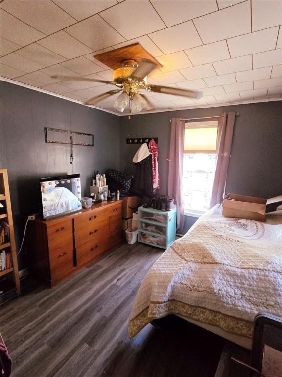 bedroom featuring ceiling fan, crown molding, and dark wood-type flooring