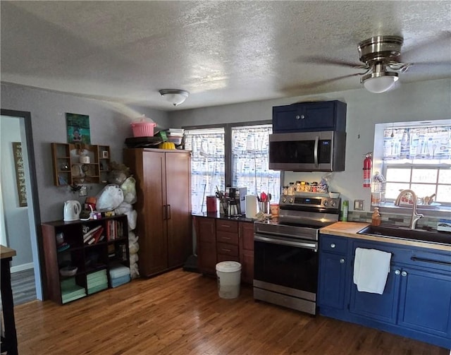 kitchen featuring sink, stainless steel appliances, dark hardwood / wood-style floors, blue cabinets, and a textured ceiling