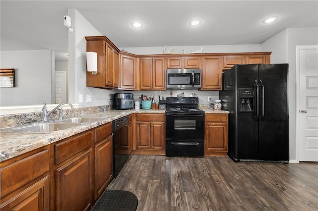 kitchen featuring sink, dark hardwood / wood-style floors, light stone counters, and black appliances