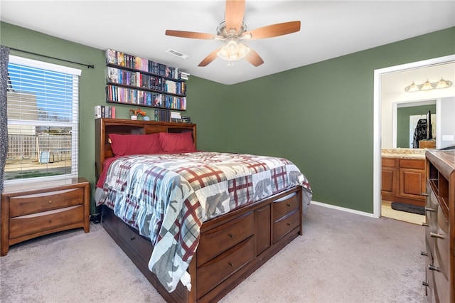 carpeted bedroom with ensuite bath and ceiling fan