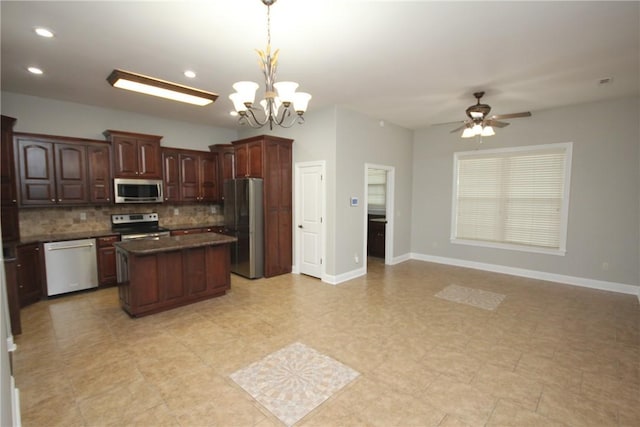 kitchen with a center island, stainless steel appliances, decorative light fixtures, decorative backsplash, and ceiling fan with notable chandelier