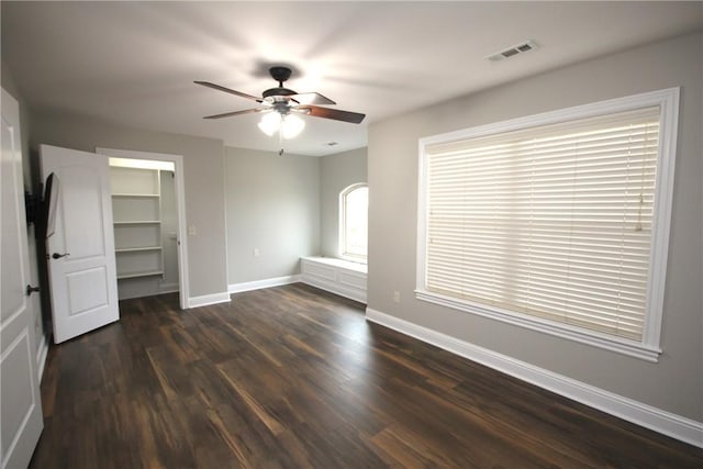 unfurnished bedroom featuring ceiling fan, dark hardwood / wood-style floors, and a spacious closet