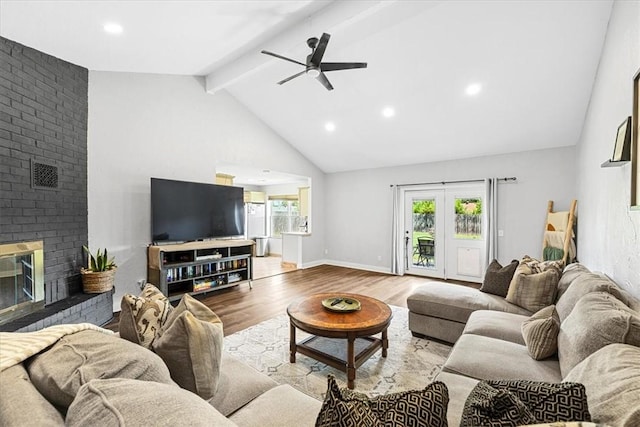 living room with lofted ceiling with beams, ceiling fan, light hardwood / wood-style floors, and a brick fireplace