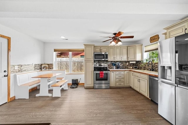 kitchen featuring stainless steel appliances, ceiling fan, sink, cream cabinets, and hardwood / wood-style floors