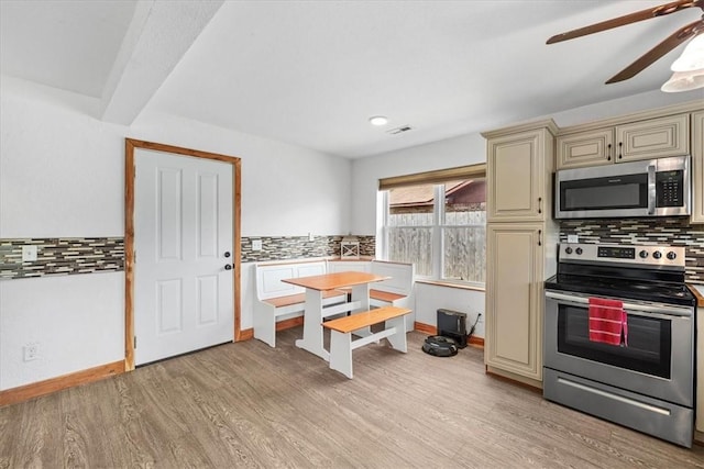 kitchen featuring ceiling fan, backsplash, cream cabinets, appliances with stainless steel finishes, and light wood-type flooring