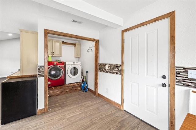 laundry area featuring washer and clothes dryer, cabinets, and light wood-type flooring