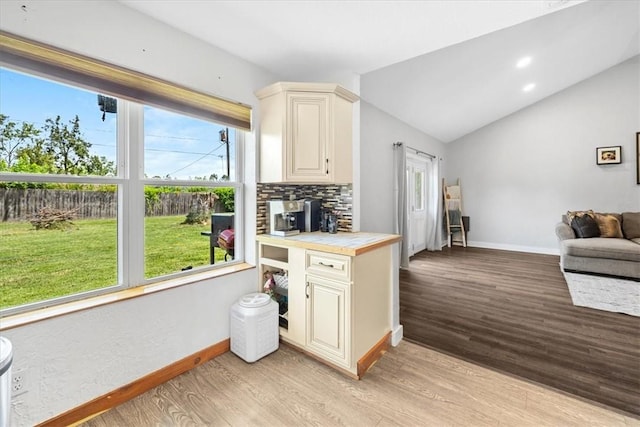 kitchen featuring backsplash, light hardwood / wood-style flooring, plenty of natural light, and lofted ceiling