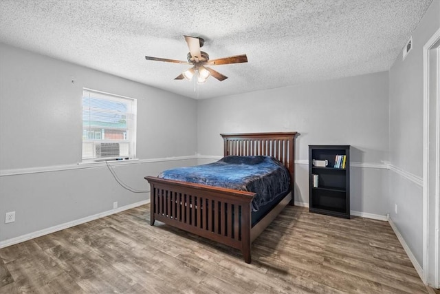 bedroom featuring hardwood / wood-style flooring, ceiling fan, cooling unit, and a textured ceiling