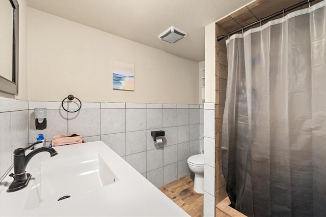 bathroom with a shower with shower curtain, toilet, tile walls, and sink