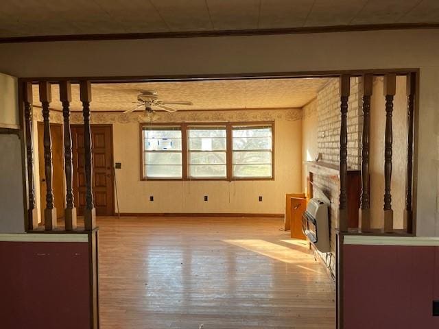 unfurnished living room with heating unit, ceiling fan, and light hardwood / wood-style flooring