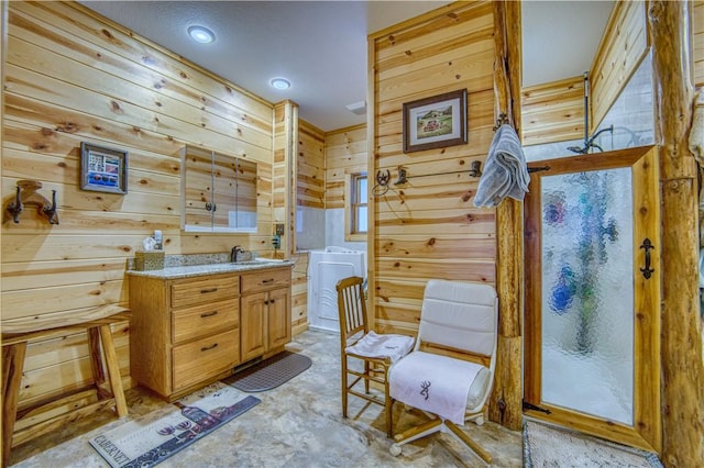 bathroom featuring a shower, washer / clothes dryer, wooden walls, and vanity