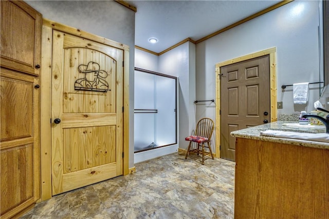 interior space featuring sink, a shower with door, and ornamental molding