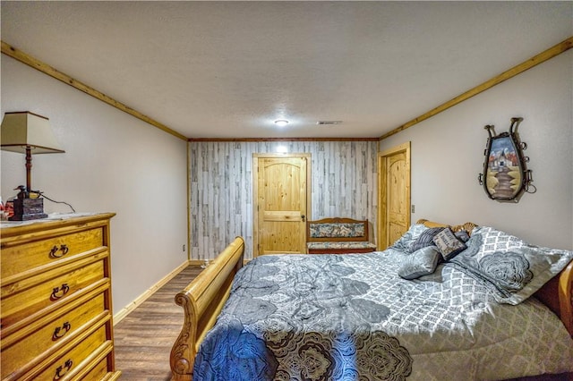 bedroom with wood-type flooring, crown molding, and wood walls