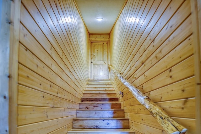 stairs with a textured ceiling and wooden walls