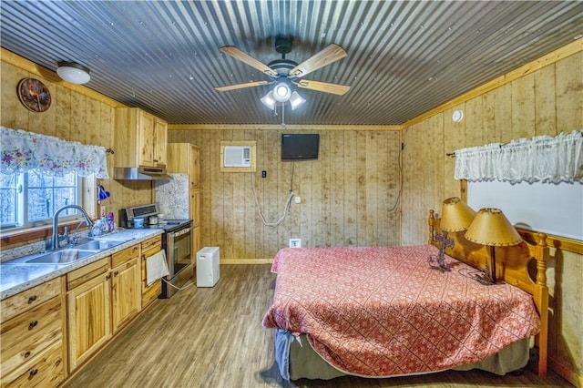 bedroom featuring ceiling fan, sink, wooden walls, and light hardwood / wood-style flooring