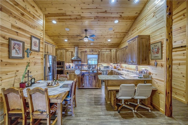 kitchen featuring dark hardwood / wood-style flooring, wood ceiling, stainless steel appliances, wall chimney range hood, and wood walls