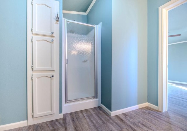 bathroom featuring hardwood / wood-style floors, a shower with shower door, vaulted ceiling, and ornamental molding