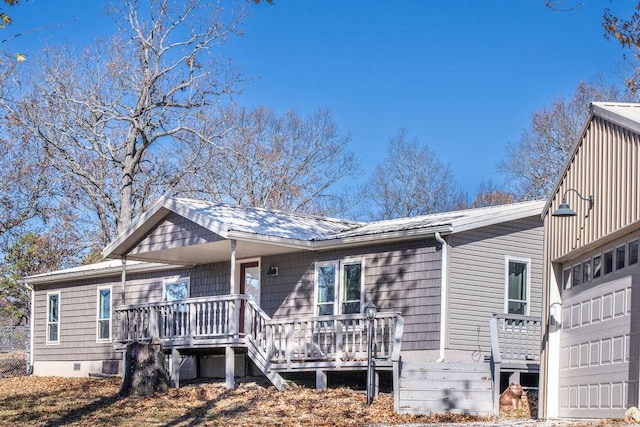 rear view of property featuring a garage and a wooden deck