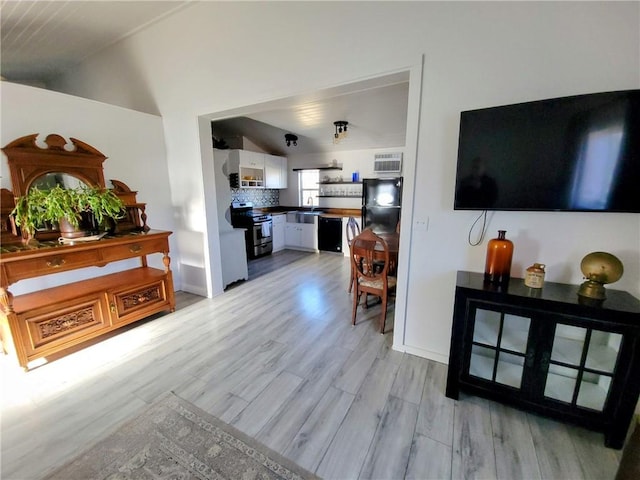 living room with light hardwood / wood-style floors, lofted ceiling, and sink