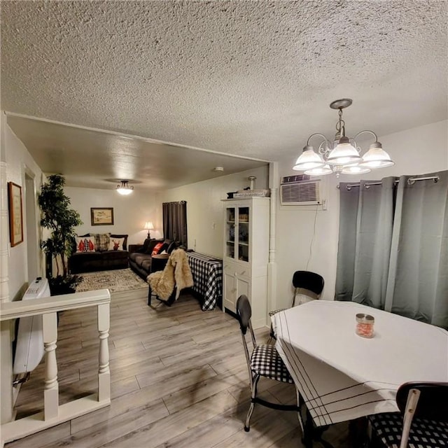 dining area featuring a textured ceiling, light hardwood / wood-style flooring, a wall mounted air conditioner, and a notable chandelier