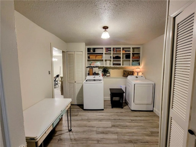 laundry area featuring washing machine and dryer, a textured ceiling, and light wood-type flooring