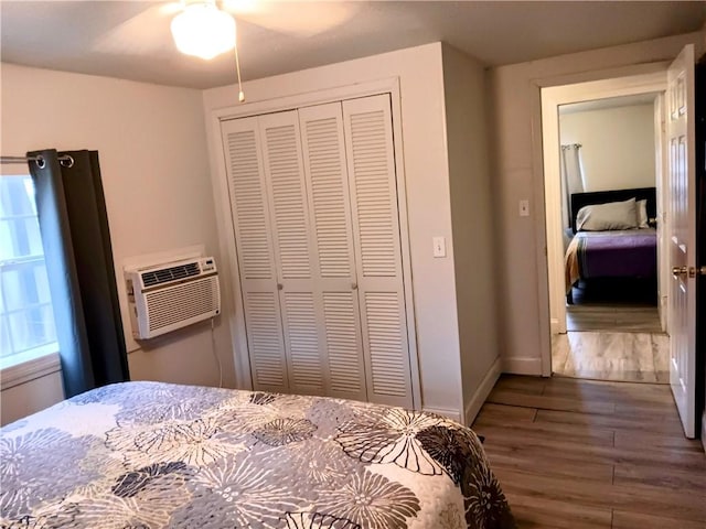 bedroom featuring ceiling fan, a closet, dark hardwood / wood-style flooring, and a wall mounted AC