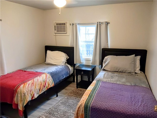 bedroom featuring wood-type flooring and an AC wall unit