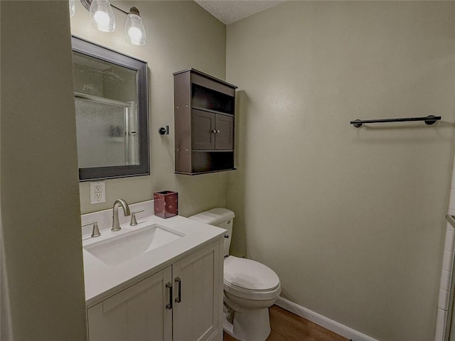 bathroom with vanity, a textured ceiling, a shower with door, hardwood / wood-style floors, and toilet