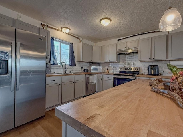 kitchen with butcher block counters, sink, hanging light fixtures, gray cabinets, and appliances with stainless steel finishes