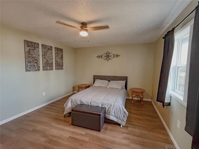 bedroom with a textured ceiling, light hardwood / wood-style flooring, and ceiling fan