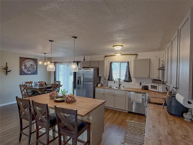 kitchen featuring appliances with stainless steel finishes, sink, pendant lighting, an inviting chandelier, and a center island