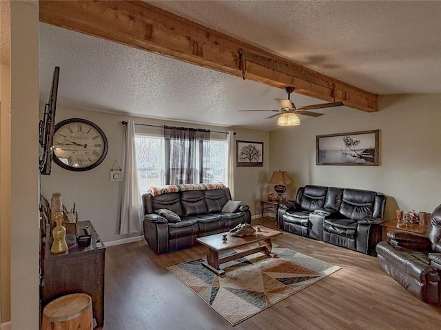 living room with beam ceiling, a textured ceiling, dark hardwood / wood-style floors, and ceiling fan