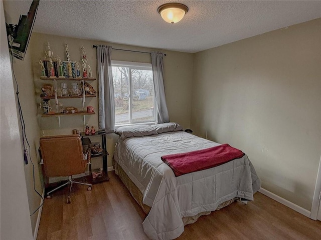 bedroom with wood-type flooring and a textured ceiling