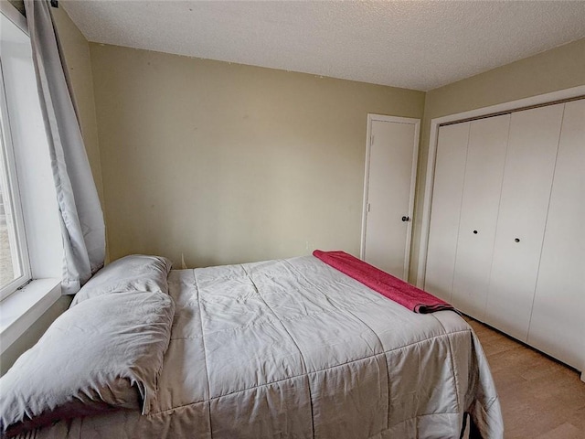 bedroom featuring light wood-type flooring, a textured ceiling, and a closet