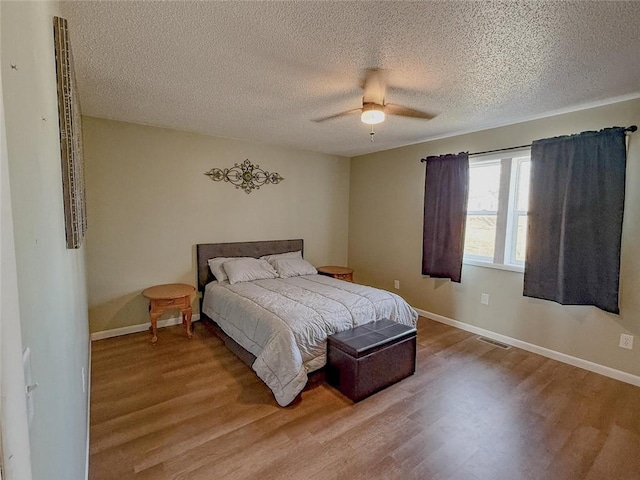 bedroom with ceiling fan, a textured ceiling, and light hardwood / wood-style flooring