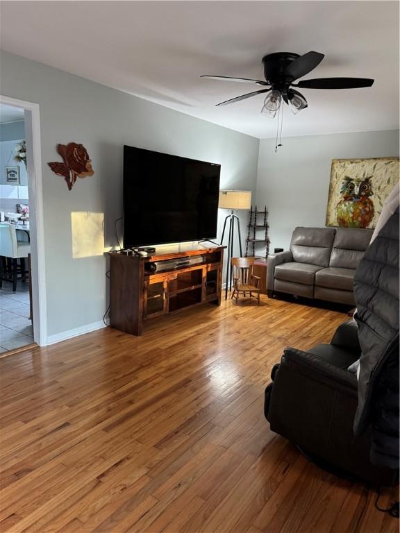 living room featuring baseboards, a ceiling fan, and wood finished floors