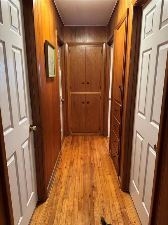 hall with wooden walls and light wood-type flooring