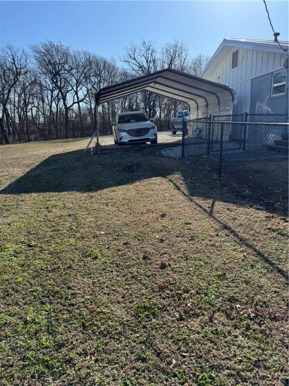 view of yard with a carport, dirt driveway, and fence