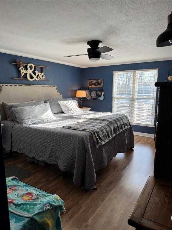 bedroom featuring ceiling fan, a textured ceiling, wood finished floors, and ornamental molding