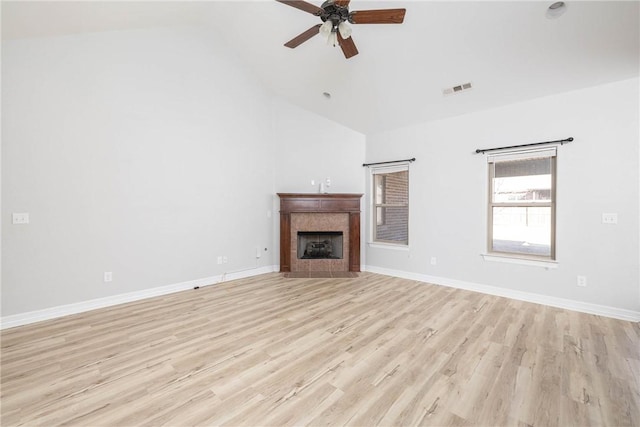 unfurnished living room with a tile fireplace, vaulted ceiling, light hardwood / wood-style flooring, and ceiling fan