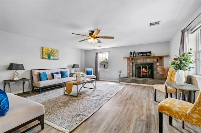 living room with a tile fireplace, ceiling fan, and hardwood / wood-style floors