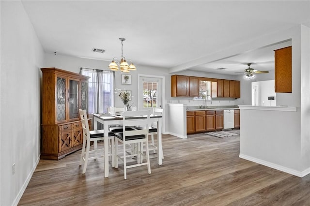 dining room featuring hardwood / wood-style flooring, ceiling fan with notable chandelier, beam ceiling, and sink