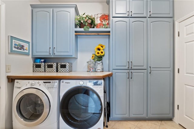 laundry area with cabinets, washing machine and dryer, and light tile patterned flooring