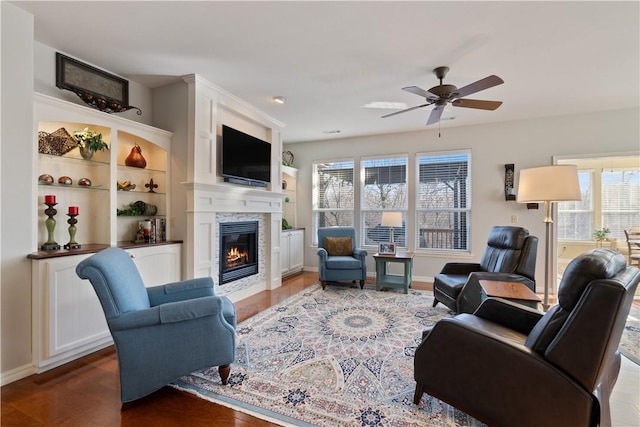 living room featuring ceiling fan, a healthy amount of sunlight, wood-type flooring, and a fireplace