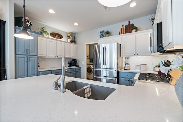 kitchen featuring decorative light fixtures, stainless steel fridge, washer / dryer, and white cabinetry