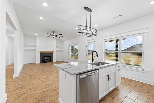 kitchen with built in shelves, sink, stainless steel dishwasher, pendant lighting, and white cabinets