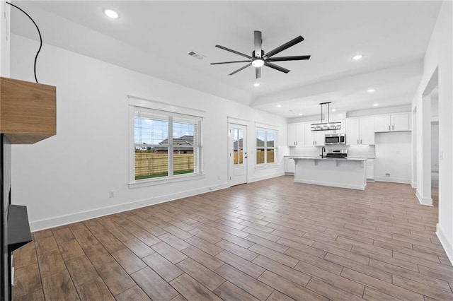 unfurnished living room with ceiling fan and sink