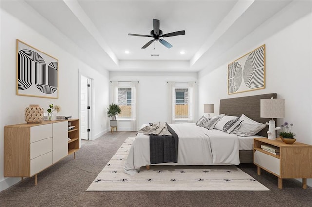 bedroom featuring dark colored carpet, a tray ceiling, and ceiling fan