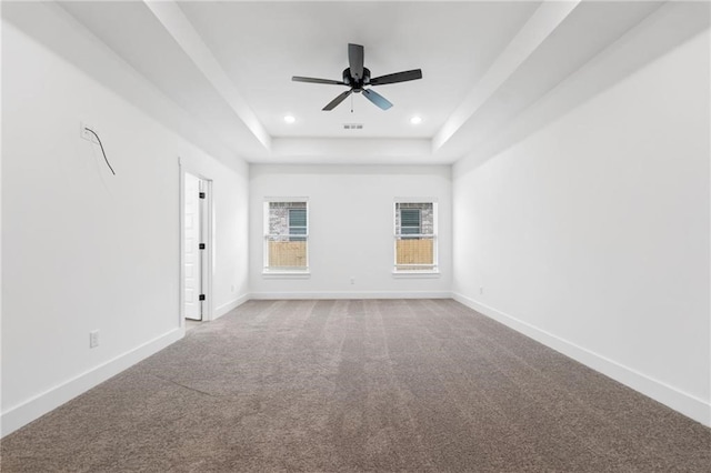 empty room featuring ceiling fan, carpet floors, and a tray ceiling